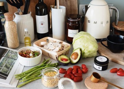 Assorted healthy food and vegetables set locating on gray countertop next to various utensils and appliances during cooking in stylish kitchen
