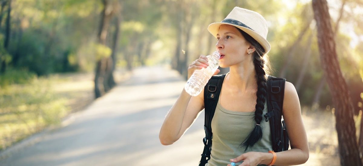 a woman in a hat drinking water from a bottle
