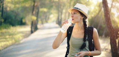 a woman in a hat drinking water from a bottle
