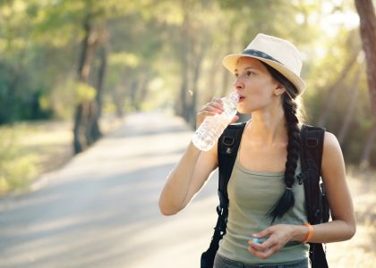a woman in a hat drinking water from a bottle
